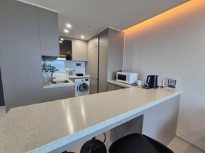 A compact kitchen with a washing machine, microwave, and coffee maker.