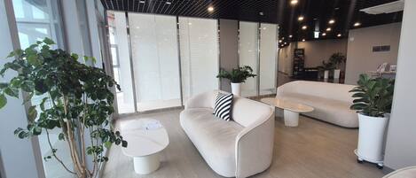 A modern interior with seating areas, a coffee table, and potted plants.