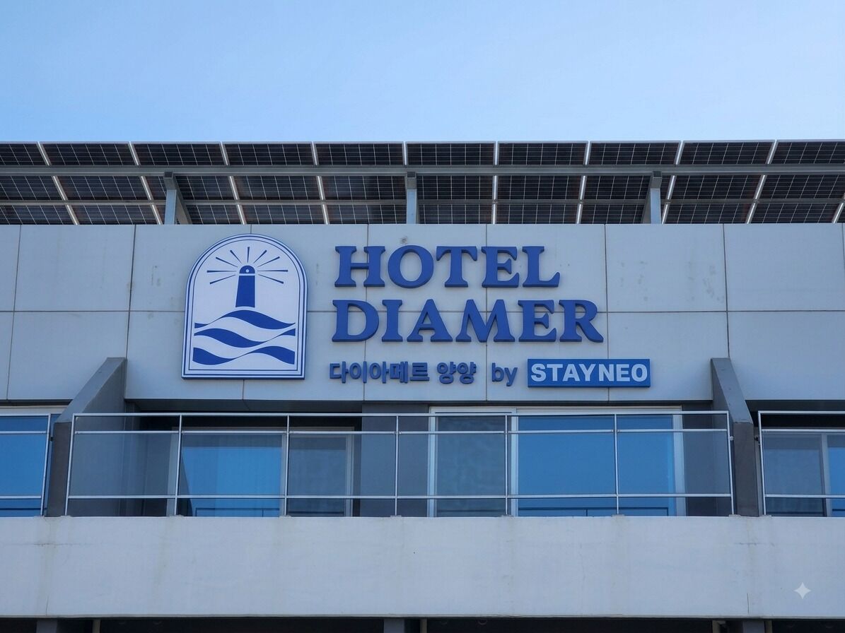 Un letrero de hotel con el nombre 'HOTEL DIAMER' y un logotipo que presenta una montaña y olas estilizadas.