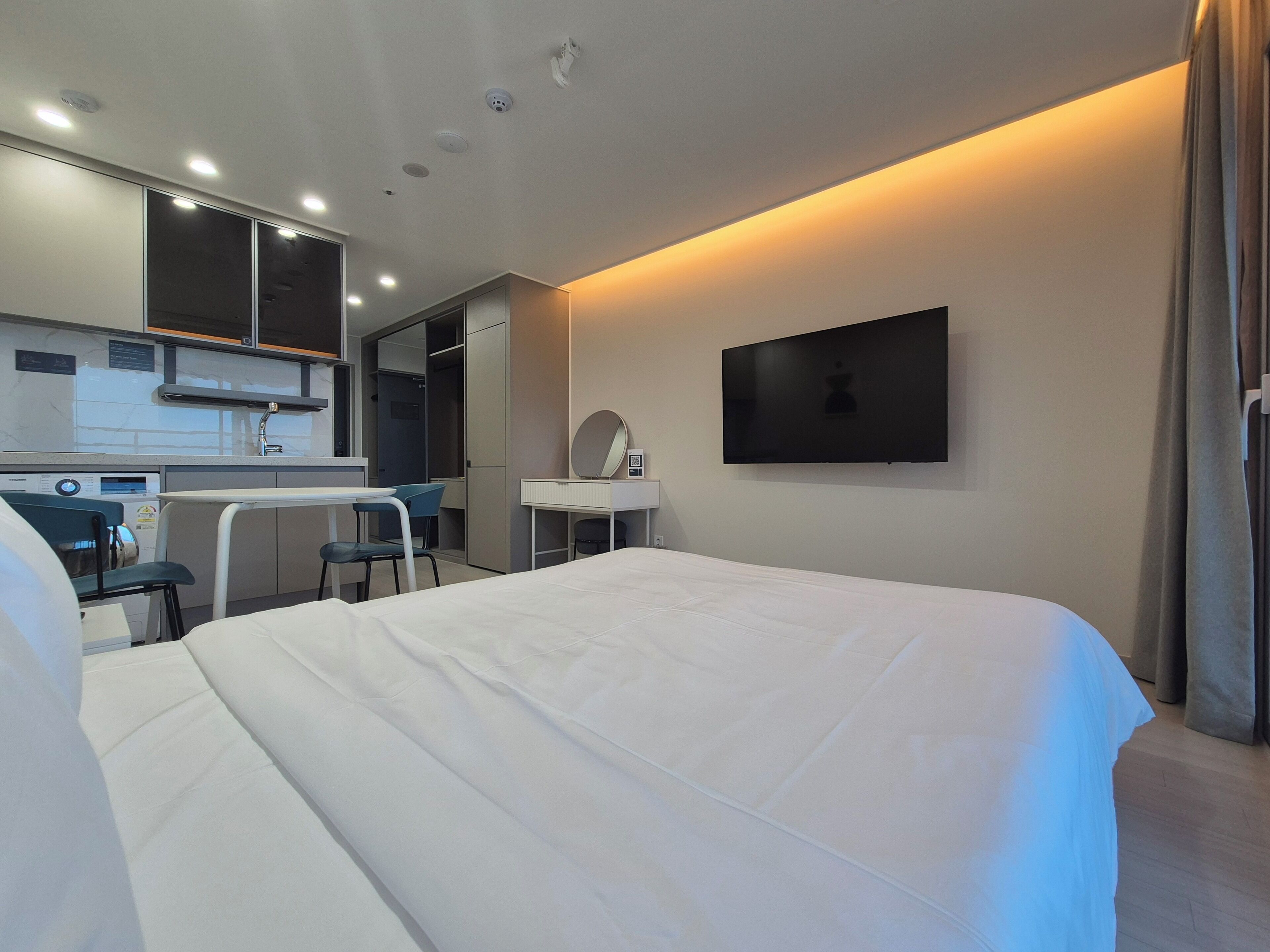 A hotel room with a bed, a desk, a chair, a TV, and a mirror.