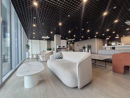 Un moderno vestíbulo de hotel con áreas de estar, una recepción y un amplio ventanal que proporciona luz natural.