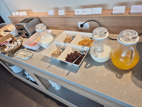 A breakfast buffet with various cereals, a milk pitcher, and a juice dispenser. - Diamer Hotel Yangyang By Stayneo (Yangyang)