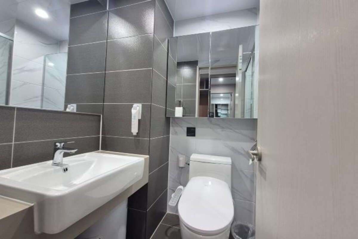 A modern bathroom with a white sink, toilet, and mirror.