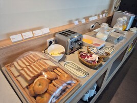 A breakfast buffet with bread, butter, jam, and a toaster.
