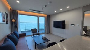 A modern hotel room with a large window, a flat-screen TV, a sofa, a coffee table, and an air conditioning unit. - Diamer Hotel Yangyang By Stayneo (Yangyang)