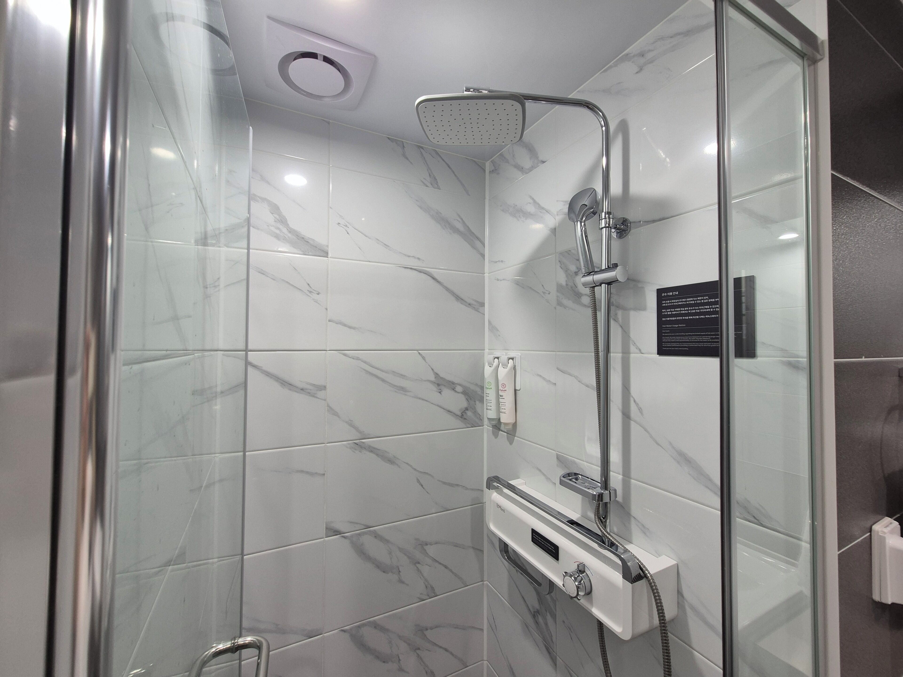 Una ducha moderna con cabezal de ducha de mano y panel de control en la pared.