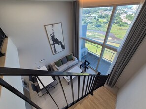 A modern living room with a sofa, a coffee table, and a view of a green landscape through large windows. - Diamer Hotel Yangyang By Stayneo (Yangyang)