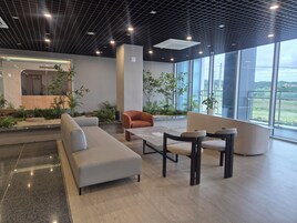 Un vestíbulo moderno con zona de estar, mostrador de recepción y amplias ventanas con vistas.