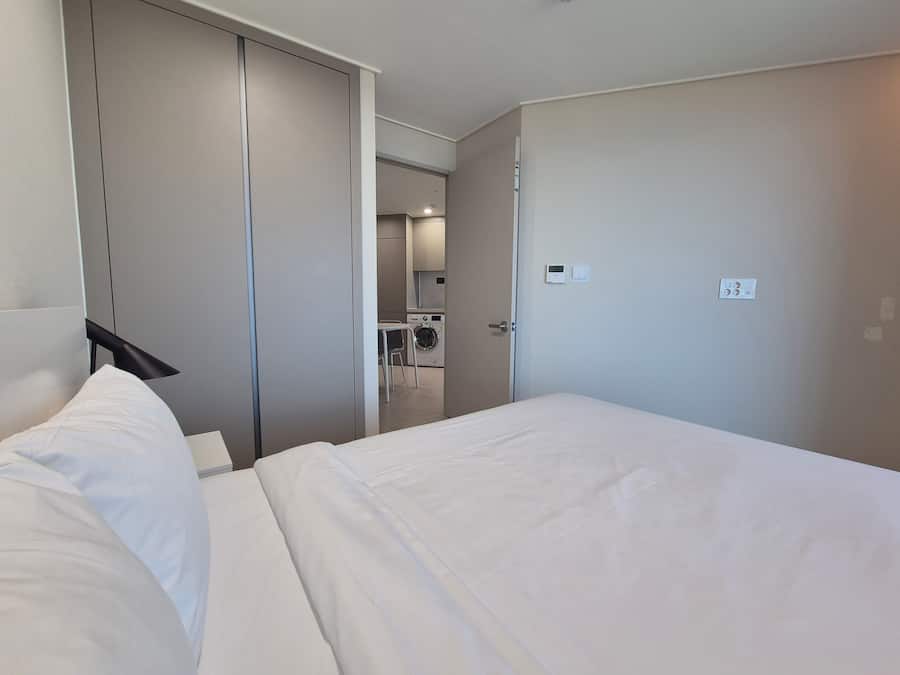A hotel room with a bed, a wardrobe, and a small kitchenette area.