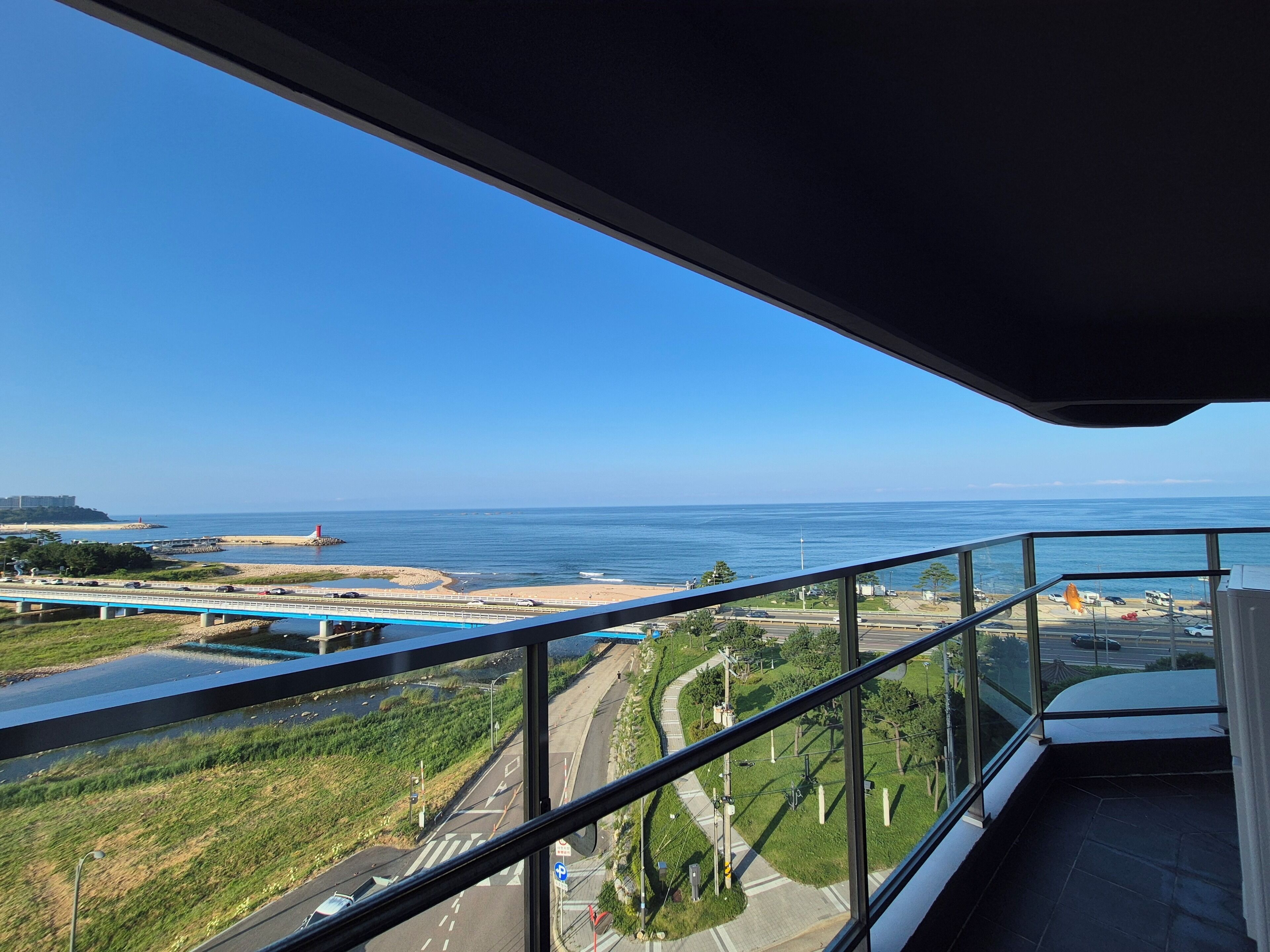 A balcony with a view of a coastal road, beach, and ocean.