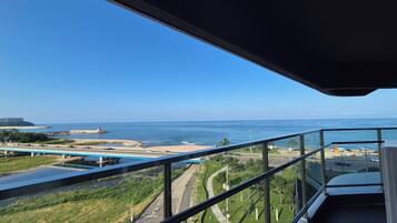 A balcony with a view of a coastal road, beach, and ocean.