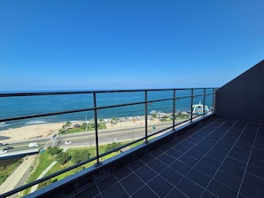A balcony with a view of the ocean and a beach.
