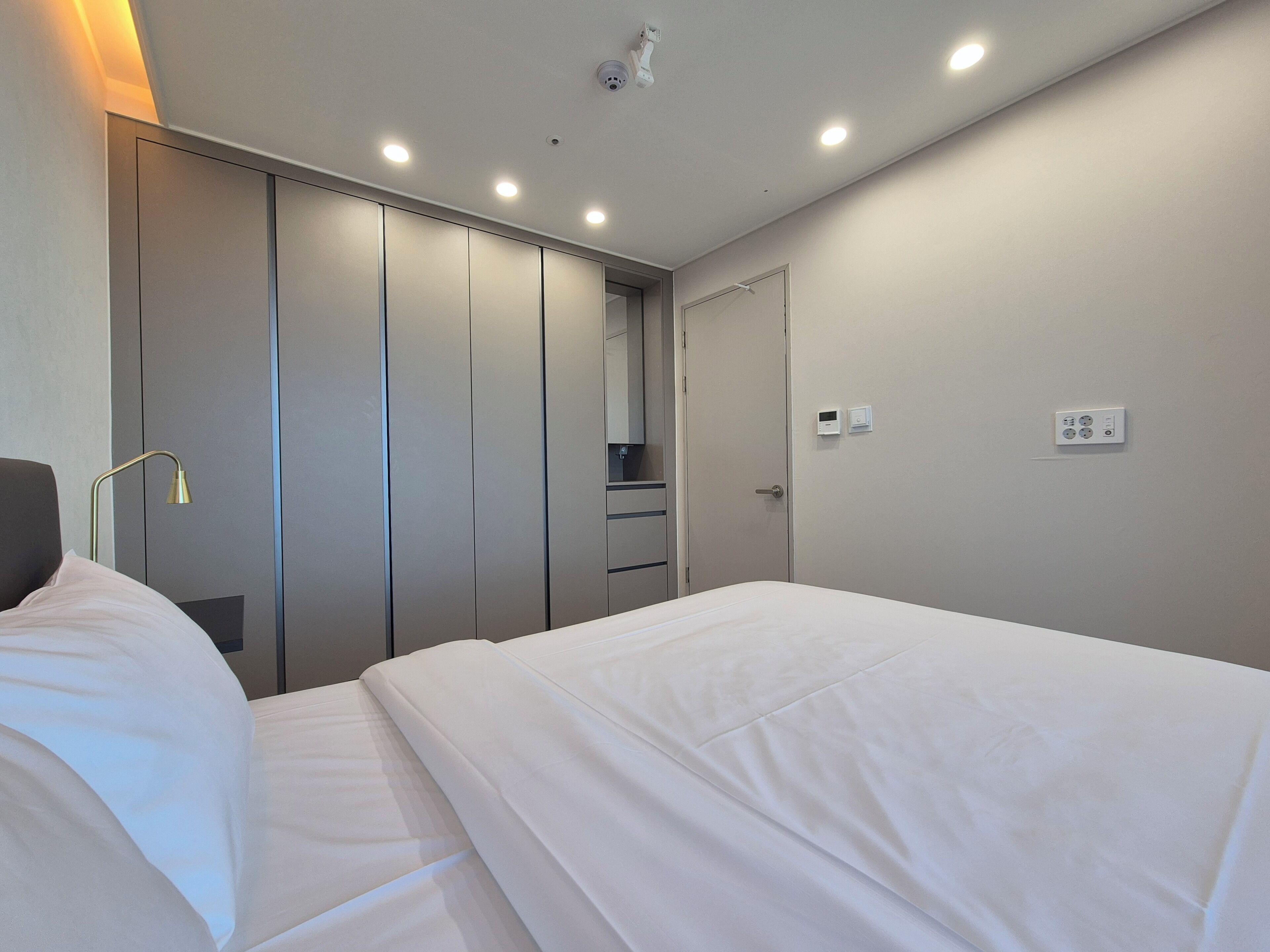 A hotel room with a bed, a wardrobe, a mirror, and a wall socket.