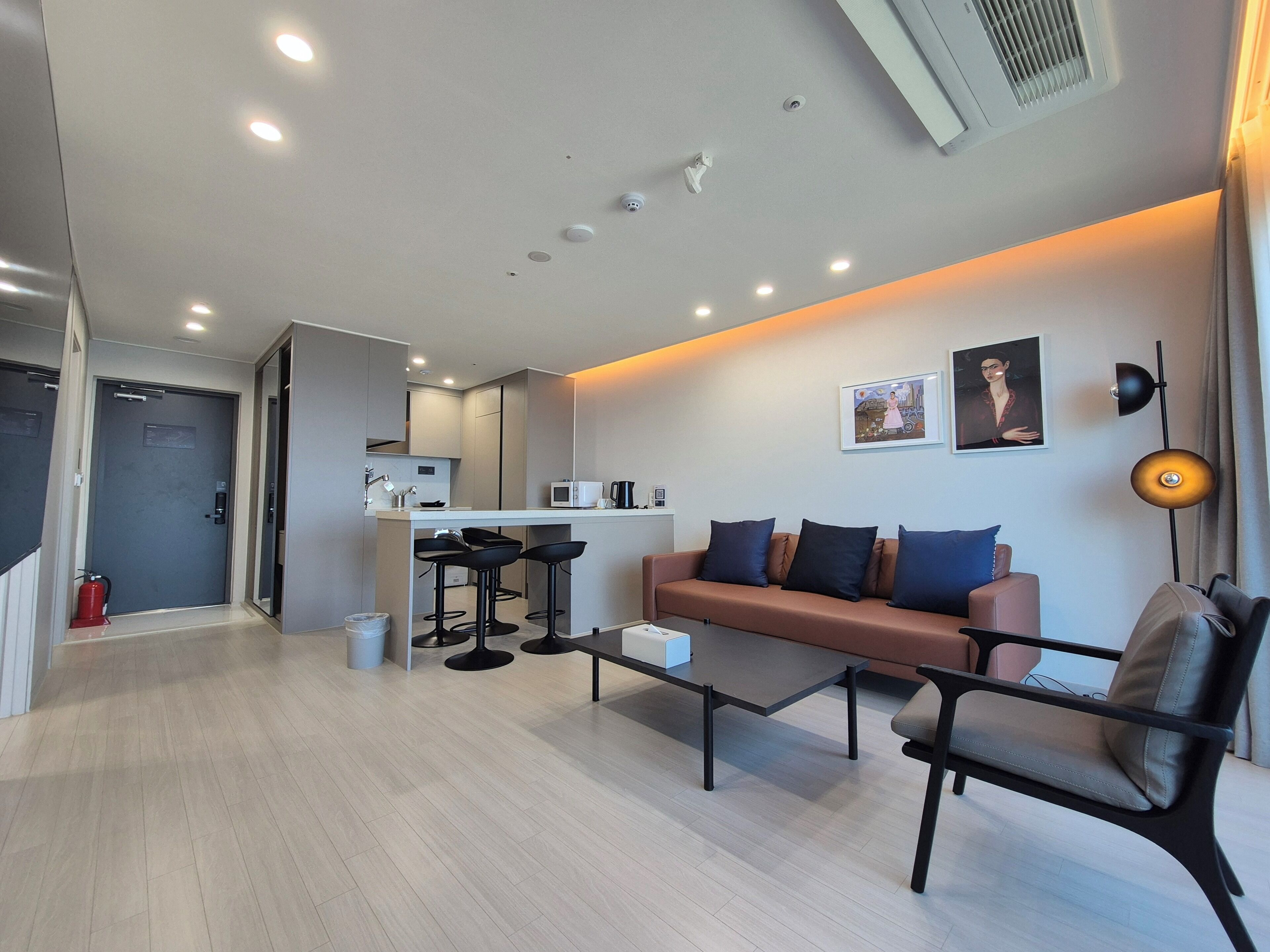 A modern living room with a sofa, a coffee table, and a dining area with stools.