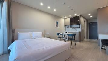 Una habitación de hotel con una cama grande, una kitchenette pequeña y un baño.