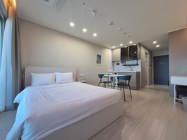 A hotel room with a large bed, a small kitchenette, and a bathroom.