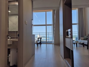 A modern hotel room with a large window, a sofa, a TV, and a bathroom with a sink and mirror. - Diamer Hotel Yangyang By Stayneo (Yangyang)