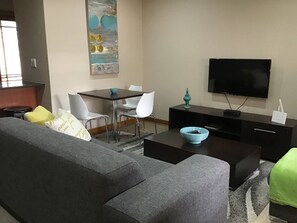Relax in this stylish living room with a comfortable sofa, a flat-screen TV, and a small dining area.