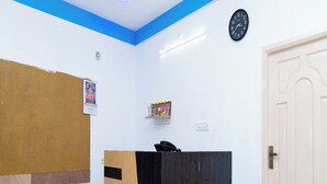 A room with a wooden cabinet, a clock, and a door. - ASK Grande Residency (Puducherry)