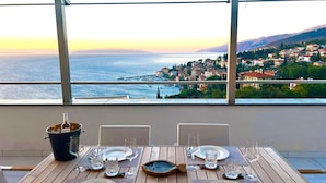 Une table dressée pour deux personnes, avec vue sur une ville côtière et la mer.