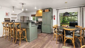 Une cuisine moderne dotée d’un îlot central, de tabourets de bar et d’une table à manger avec des chaises.
