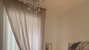 Une chambre à coucher avec un grand lit, un lustre, un miroir et un tableau accroché au mur.