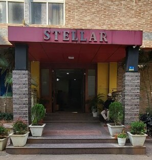 The exterior of a hotel named 'STELLAR' with a red awning, stone pillars, and potted plants at the entrance. - Hotel Stellar (Bhubaneshwar)
