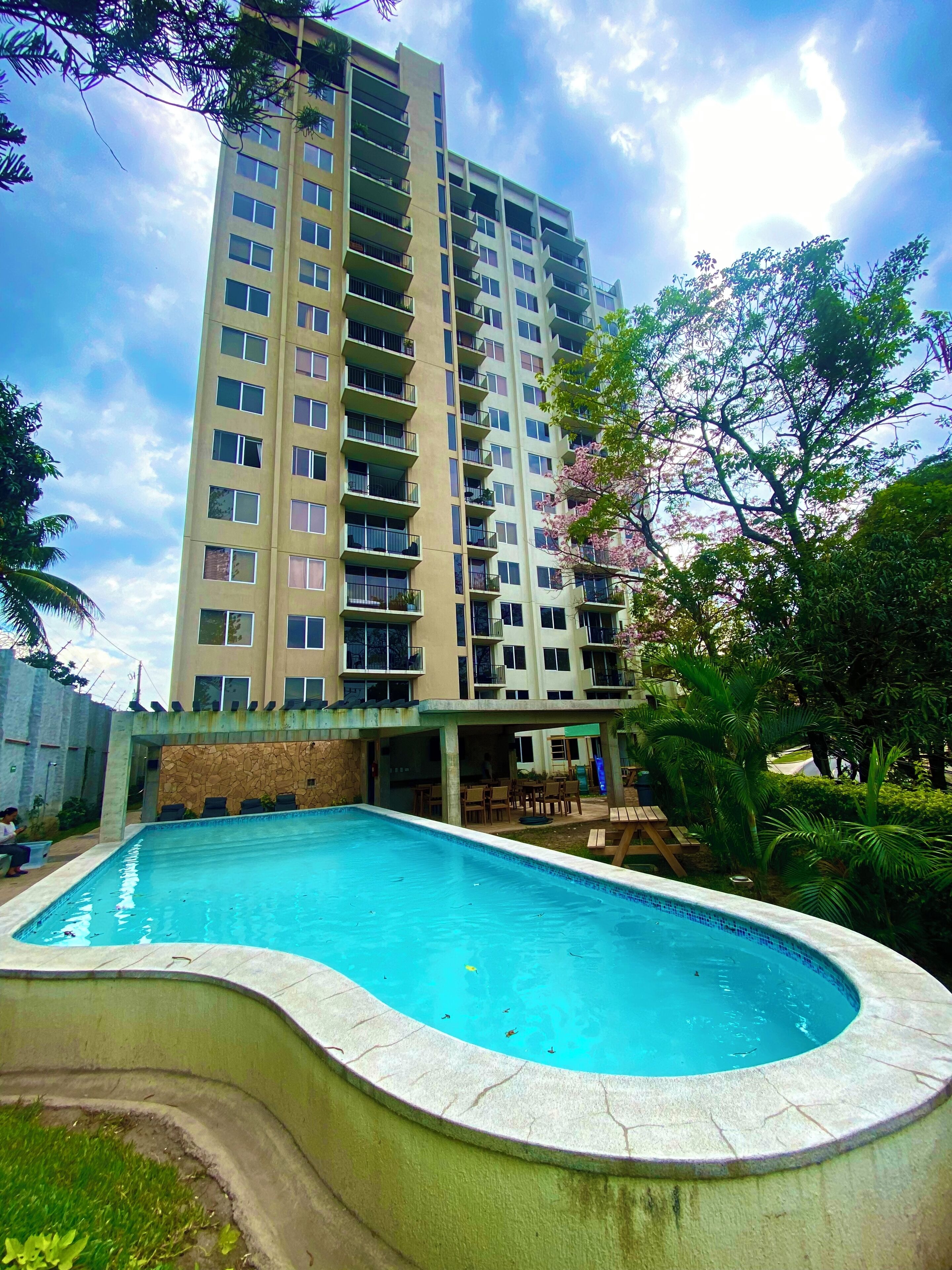 A high-rise building with a swimming pool in front.