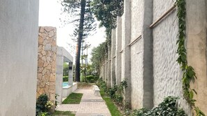 Un sendero estrecho bordeado por muros de piedra y hormigón, que conduce a la entrada de un edificio.
