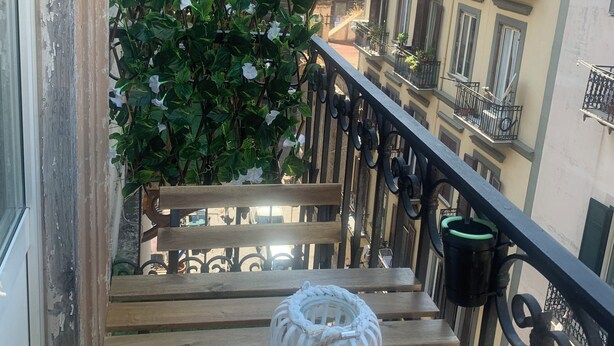 A balcony with a wooden bench, a white lantern, and a flowering plant. - AR.b&b in the heart of naples 4 (Napoli)