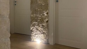 A hallway with a textured stone wall, wooden flooring, and two white doors with handles. - AR.b&b in the heart of naples 4 (Napoli)