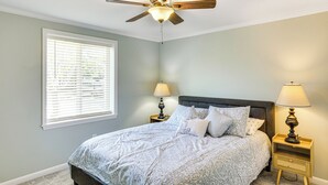 A bedroom with a bed, two bedside tables with lamps, a ceiling fan, and a window with blinds. - Lake Moultrie Access: Moncks Corner Home w/ Dock (Moncks Corner)