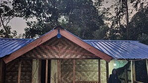 A rustic wooden structure with a corrugated metal roof, a wooden bench, and a door. - Warichora Homestay and Rooms Meghalaya (South Garo Hills)