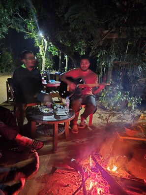 Un gruppo di persone sedute attorno a un tavolo, con un fuoco in primo piano.
