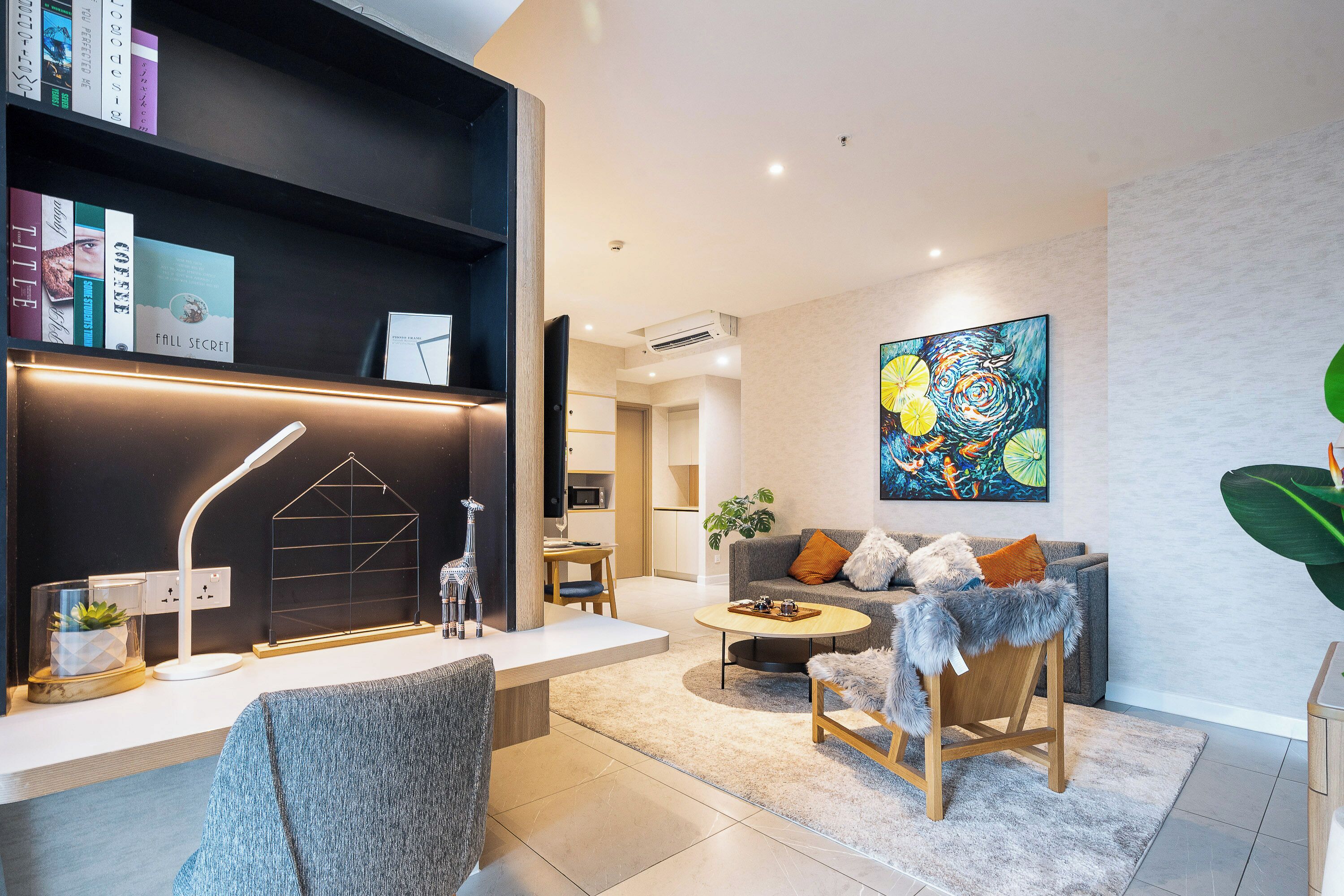 A modern living room with a bookshelf, a coffee table, a sofa, and a painting on the wall.