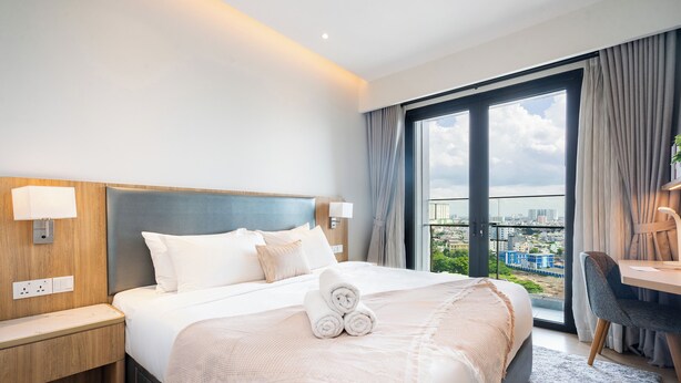 Une chambre d’hôtel moderne, dotée d’un grand lit, d’un bureau et offrant une vue sur la ville par la fenêtre.