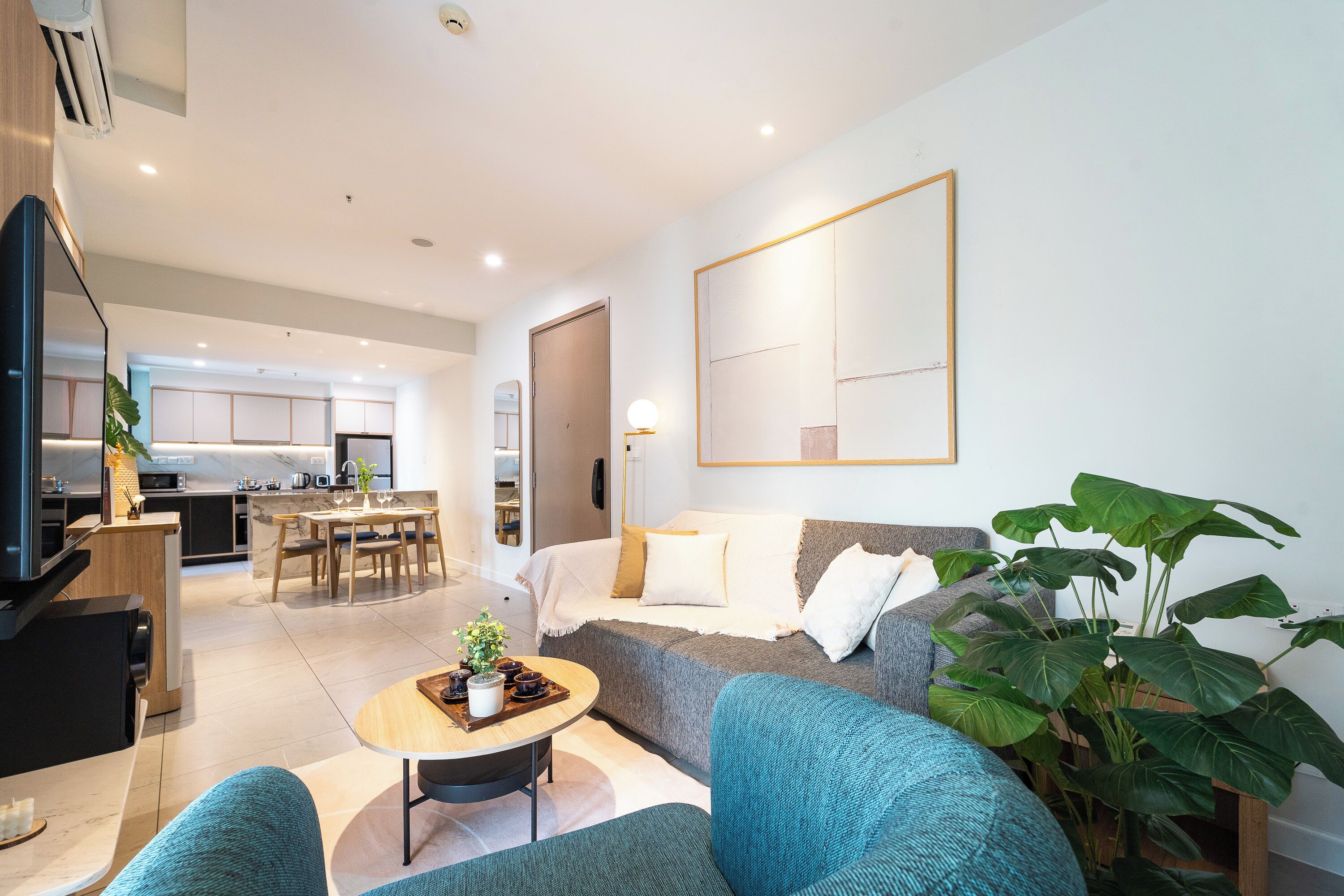 A modern living room with a sofa, coffee table, and a dining area with a table and chairs.