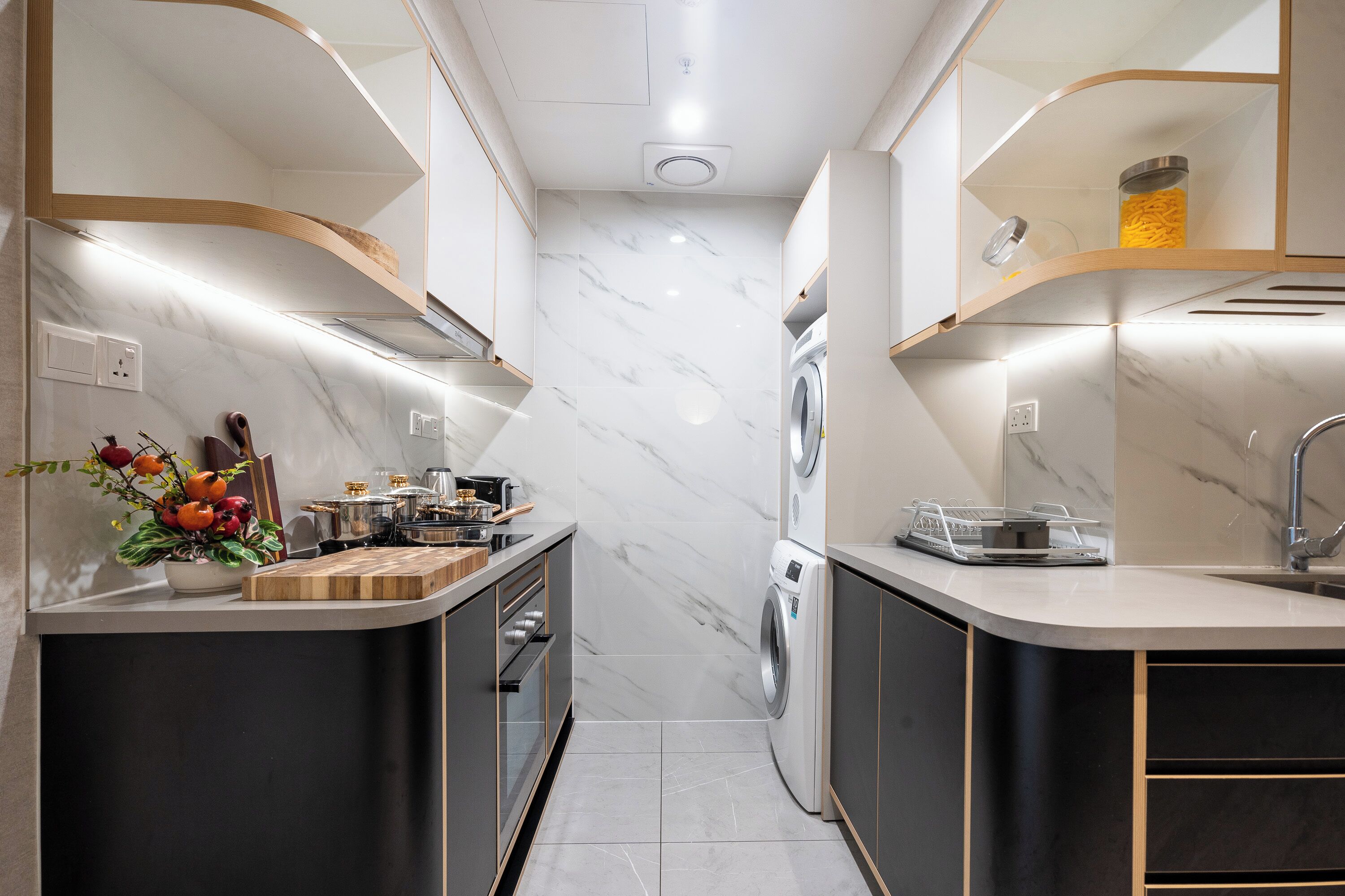 Une cuisine moderne dotée de plans de travail en marbre, d’appareils électroménagers intégrés et d’un îlot central.