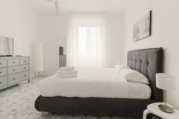 Une chambre à coucher avec un lit, une commode, un miroir et un tableau accroché au mur.