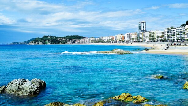 A coastal cityscape with clear blue waters, rocky shoreline, and a sandy beach. - Villas Vila in Lloret de Mar (Lloret de Mar)