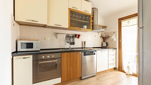 A modern kitchen with a microwave, oven, dishwasher, and wooden cabinets.