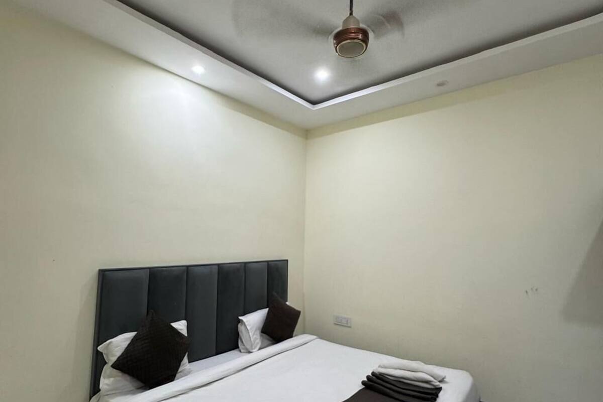 Una habitación de hotel moderna con una cama grande, cabecera oscura y un ventilador de techo.