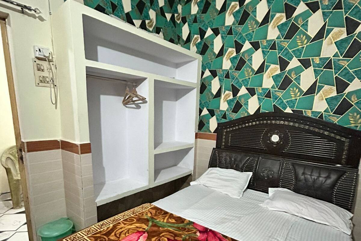 Un dormitorio con cama, armario con espacio para colgar, baño con inodoro y pared decorada.