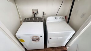 A laundry room with two stacked washers and dryers, a power outlet, and a wall-mounted electrical outlet. - Gemini Villas Gemini I (Saboga)