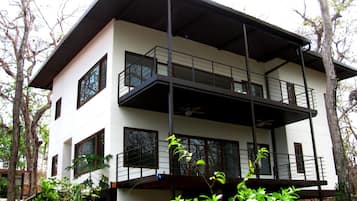 Um edifício de dois andares com teto plano, grandes janelas e varanda.