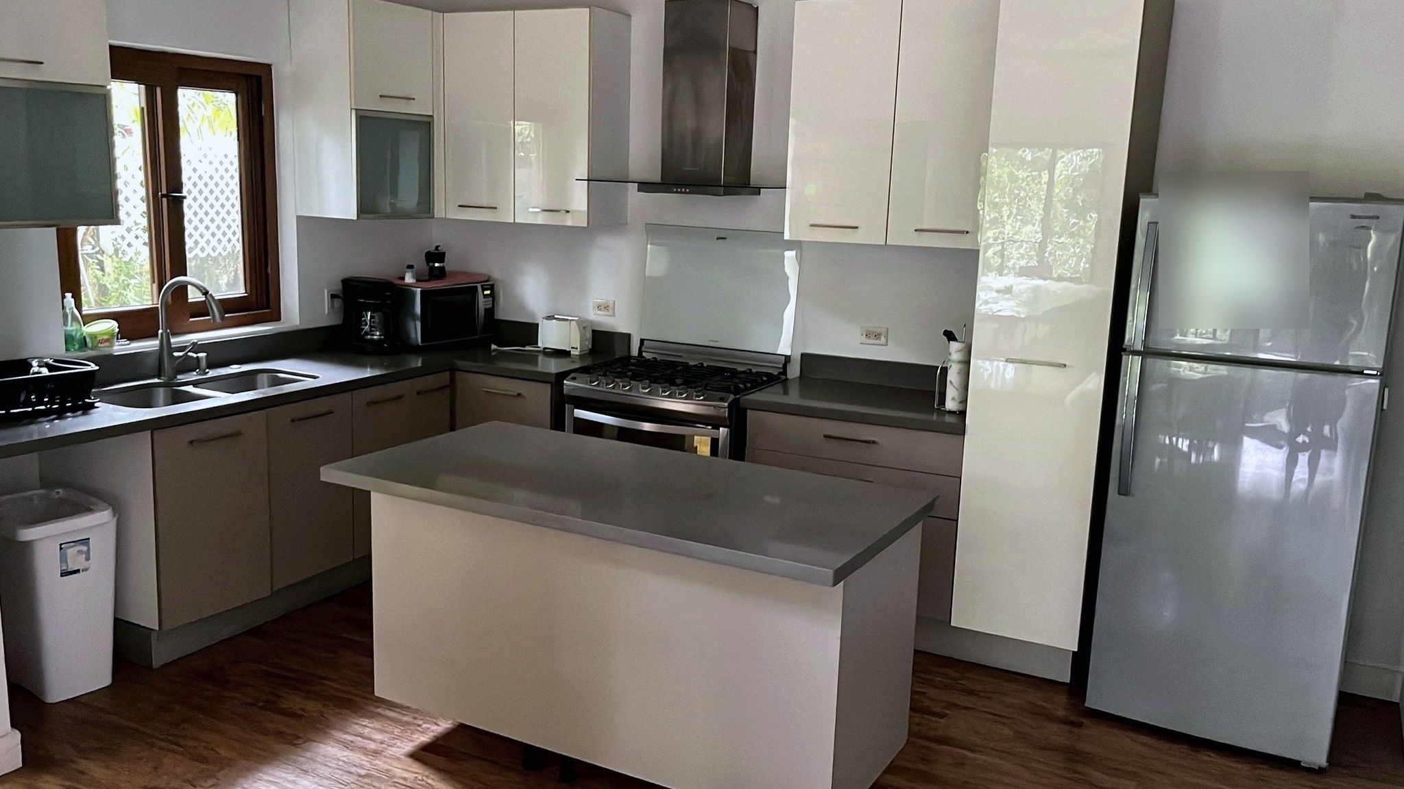 Una cocina moderna con armarios blancos, un refrigerador de acero inoxidable, horno empotrado y microondas.