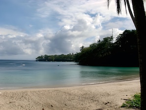 A beach with clear water, a sandy shore, and a forested area in the background. - Gemini Villas Gemini I (Saboga)