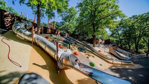 Un parque infantil con toboganes, estructuras para escalar y una zona de arena.
