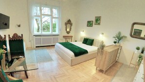 Un dormitorio con cama, cómoda, espejo, ventana y radiador.