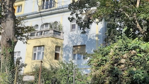 Un edificio residencial con un muro de piedra, una reja de metal y una escalera que conduce a una puerta.